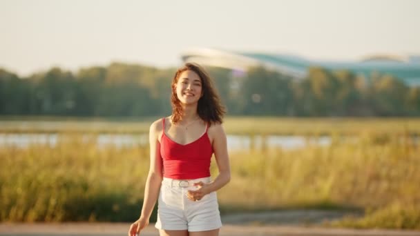 Een mooie lachende vrouw zwaaiende hand op de camera-veld en het meer — Stockvideo
