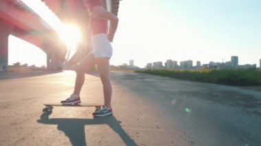 Köprü altında kaykay sürme genç kadın - gün batımı