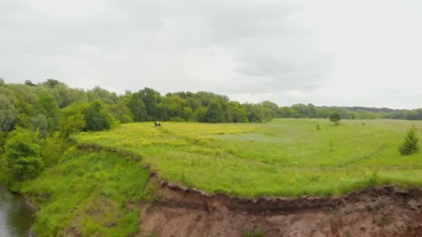 Un paysage de la rivière et un champ verdoyant - une personne qui monte à cheval 