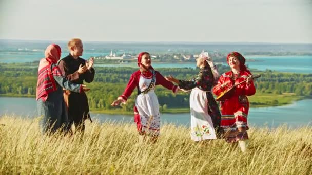 Ung ensemble i traditionella ryska kläder dansar på fältet av musiken — Stockvideo