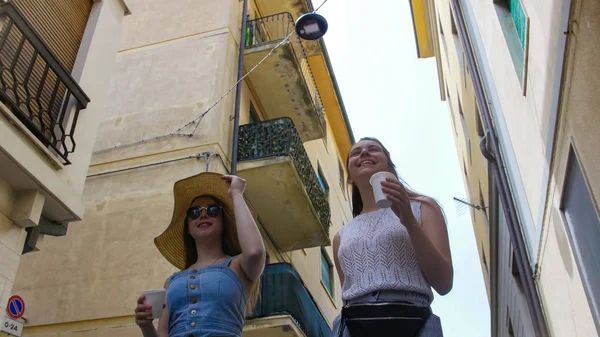 Dos mujeres atractivas caminan por la ciudad en la calle estrecha —  Fotos de Stock