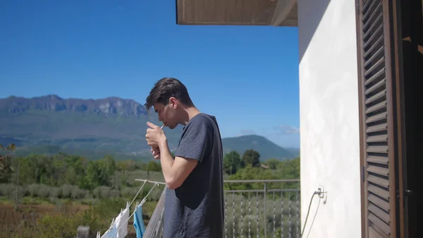 若い男がバルコニーにタバコを点灯 - 山の風景を背景に — ストック写真