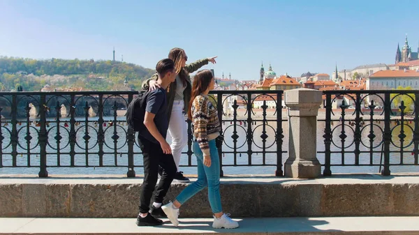 Tres amigos caminando por el puente y mirando a su alrededor en la Checa, Praga —  Fotos de Stock