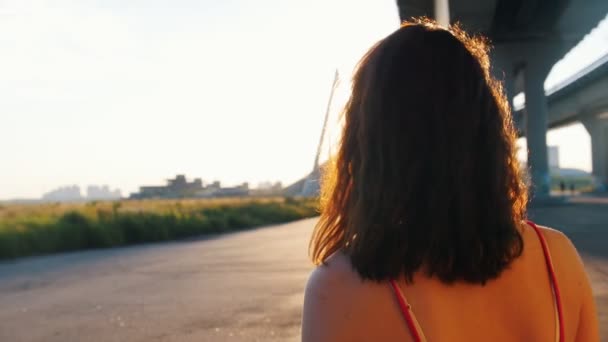 Jeune femme se tournant vers la caméra, sourire et aller faire du skateboard - magnifique coucher de soleil — Video