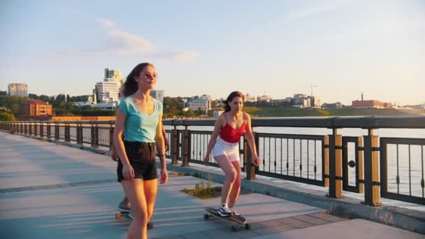 Unga leende vänner rida skateboards på vattnet på en bakgrund av moderna byggnader — Stockvideo