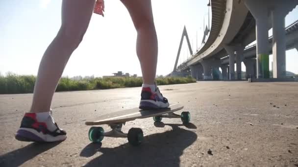 Giovane donna con belle gambe in sella skateboard al di fuori - luce solare brillante — Video Stock