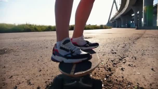 Молодая женщина в кроссовках катается на скейтборде по грязи — стоковое видео