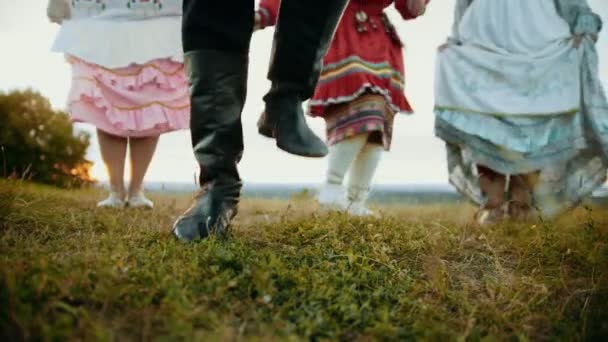 En person i svarta läderstövlar dansar på det gröna fältet — Stockvideo