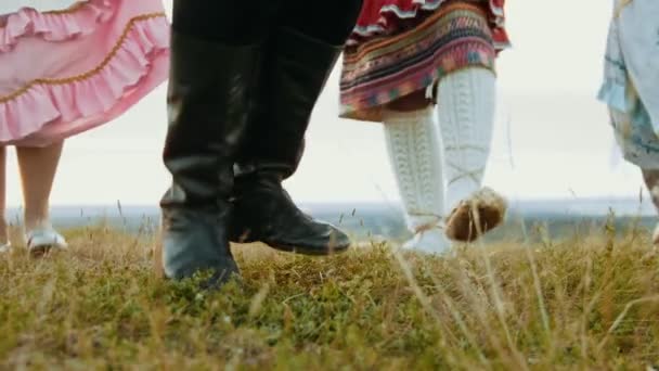 Een persoon in zwart leren laarzen dansen op het groene veld-dansen in ensemble — Stockvideo