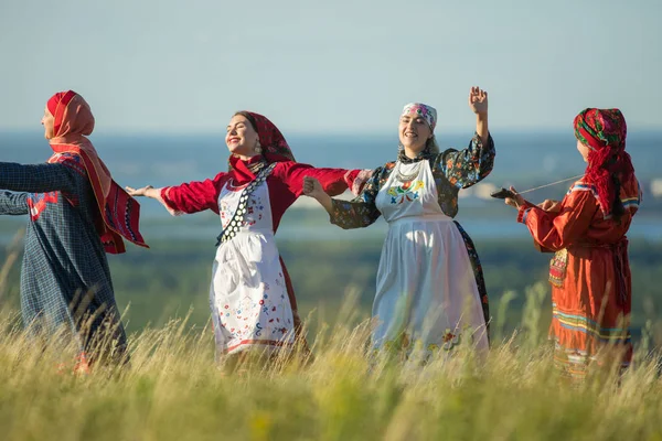 Молодые женщины в традиционной русской одежде танцуют на поле — стоковое фото