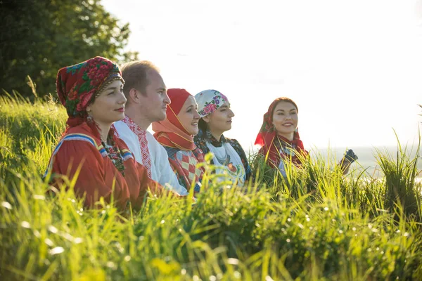 Люди в традиционной русской одежде стоят на поле в высокой траве — стоковое фото