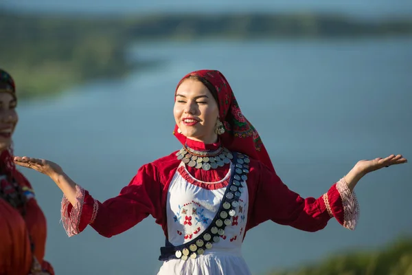 Молодая улыбающаяся женщина в традиционной русской одежде танцует на поле — стоковое фото