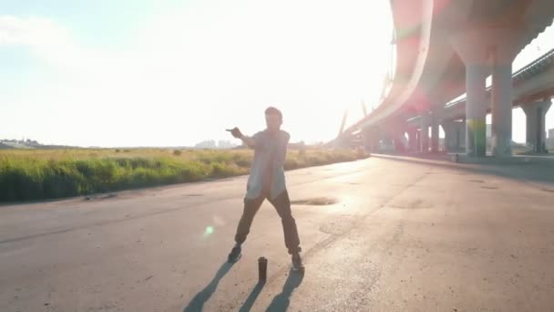 Mladý stylový muž volný styl do tančící pod mostem hudbou z reproduktoru — Stock video