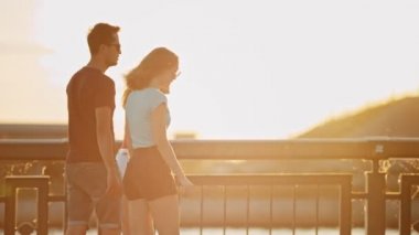 Genç arkadaşlar güzel bir parlak gün batımında bir rıhtım üzerinde kaykay sürme