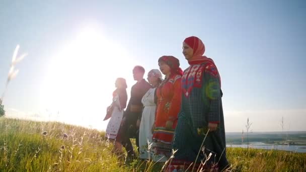 Kvinnor och man i traditionella ryska kläder går i rad på fältet och sjunger en sång — Stockvideo