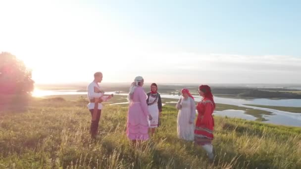 Personas con ropa tradicional rusa de pie en la hierba en la colina verde y bailando - Uno de ellos juega balalaika — Vídeos de Stock