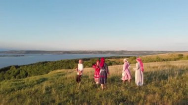 Bir adam yeşil çayırda geleneksel Rus cüppegenç kadınlar için balalaika çalış