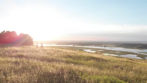 Pessoas em roupas tradicionais russas dançando à distância contra o pôr do sol — Vídeo de Stock