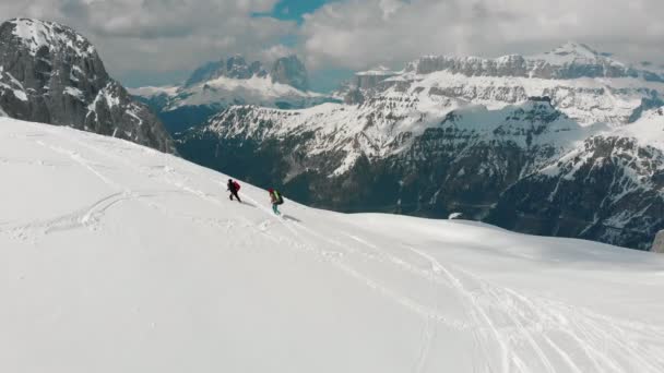 Dolomites'teki karlı dağda büyük sırt çantalarıyla yukarı doğru yürüyen iki gezgin kadın — Stok video