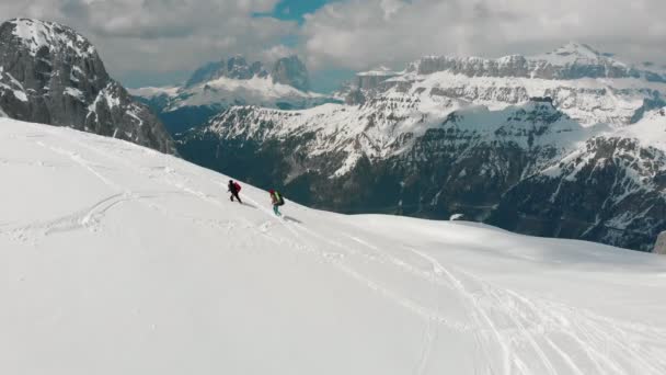 Dos mujeres viajeras caminando hacia arriba en la montaña nevada en Dolomitas con grandes mochilas — Vídeos de Stock