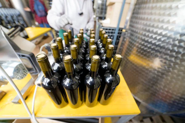 A variety of packaged wine bottles on the production table. Person working with bottles
