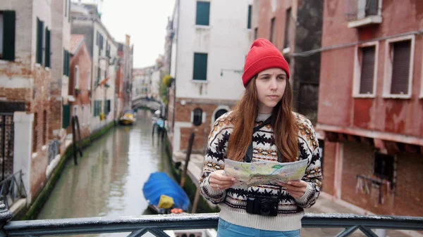 Una joven mujer confundida de pie sobre el canal de agua y mirando el mapa - Venecia, Italia —  Fotos de Stock