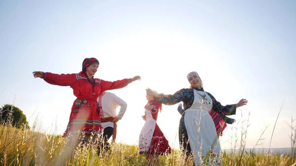 Geleneksel Rus kıyafetleri içinde mutlu insanlar sahada yuvarlak bir dans yapıyor — Stok fotoğraf