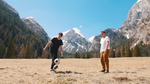 Dos jóvenes jugando al fútbol en el fondo de las montañas y el bosque - Dolomitas, Italia — Vídeos de Stock