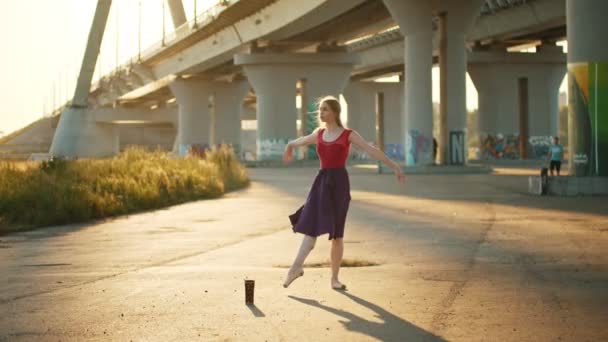 Jonge lachende vrouw ballerina dansen in de buurt van de brug — Stockvideo