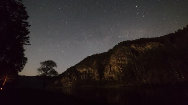 Прекрасне нічне небо, повне рухомих зірок гора з лісом — стокове відео