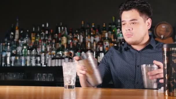 Young professional bartender effectively prepares a cocktail with a shaker and glasses — Stock Video