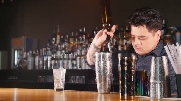 Jovem barman profissional derrama um copo de líquido em uma coqueteleira — Vídeo de Stock