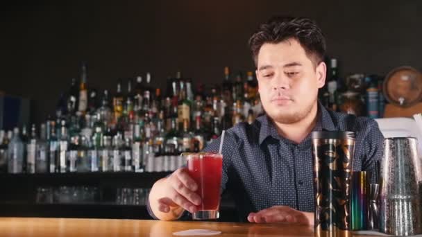 Il giovane barista professionista mette il cocktail preparato su un tovagliolo e lo porta avanti . — Video Stock
