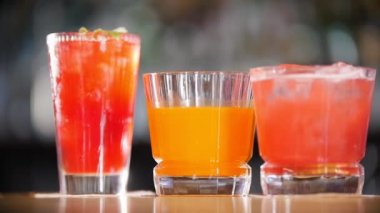 Bar konsepti - Üç bardak kokteyl rafta. Buz yukarıdan düşüyor