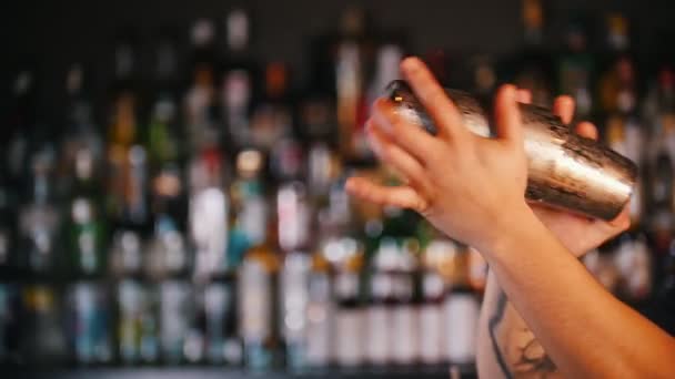 Professional young barman using a pair of glasses prevents cocktail — Stock Video