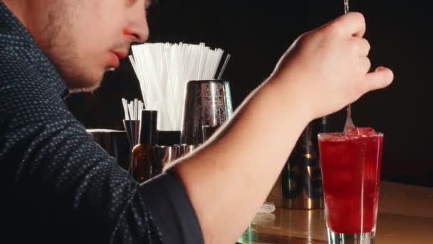 Ο μπάρμαν ανακατεύοντας το κοκτέιλ στο γυαλί χρησιμοποιώντας ένα κουτάλι του μπαρ — Αρχείο Βίντεο