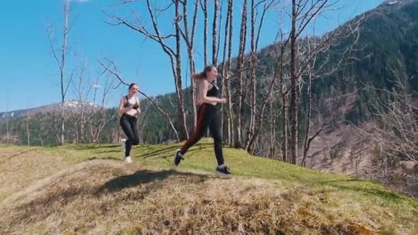 Zwei junge sportliche Frauen laufen den Hügel hinunter - Dolomiten, Italien — Stockvideo