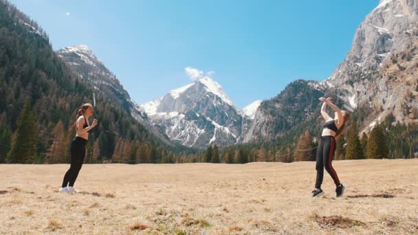 Twee jonge vrouwen spelen badminton op een achtergrond van de bergen en het bos-Dolomieten, Italië — Stockvideo