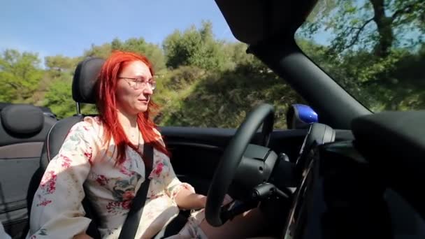 Een jonge vrouw rijdt een cabriolet tussen de bomen. — Stockvideo