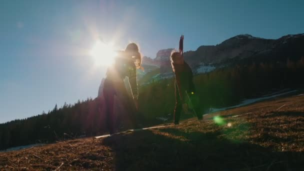 Dos mujeres jóvenes haciendo deportes al aire libre - calentando - montañas y bosques sobre un fondo — Vídeos de Stock