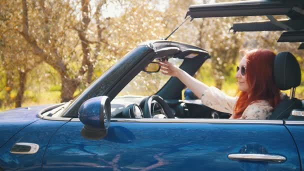 Eine junge lächelnde Frau sitzt im Cabrio und das Dach schließt sich langsam - sonniger Tag — Stockvideo