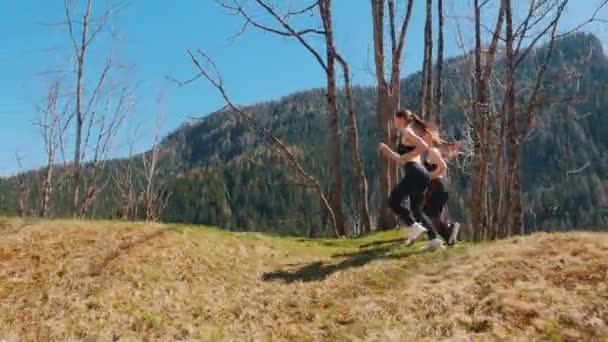 丘の上を走る2人の若いスポーツ女性 - ドロミテ、イタリア — ストック動画
