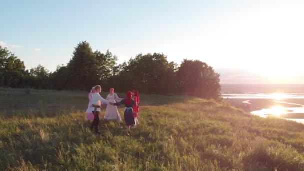 Människor i traditionella ryska kläder dansar hålla händerna på kullen — Stockvideo