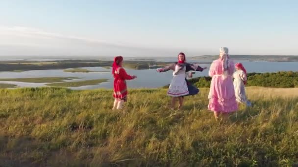 Οι άνθρωποι με παραδοσιακά ρωσικά ρούχα παίρνουν στροφές στο κέντρο και χορεύουν με την μπαλαλάικα παίζοντας — Αρχείο Βίντεο