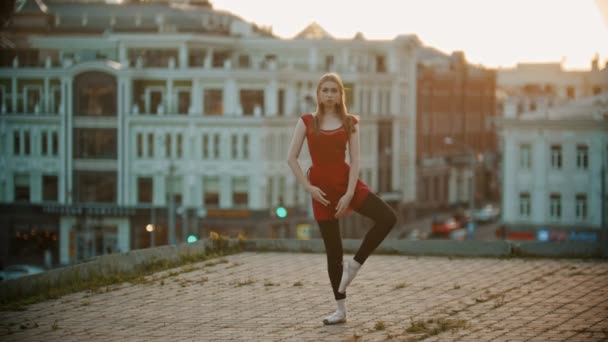 Mujer joven bailarina de entrenamiento en el techo de pie en la pose que muestra su estiramiento — Vídeos de Stock