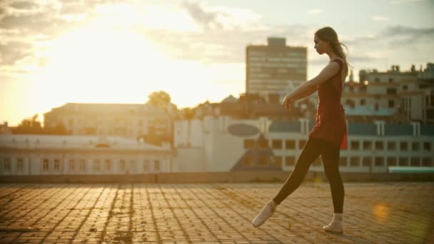 Νεαρή γυναίκα μπαλαρίνα χορεύει στην ταράτσα-τρέχει και άλμα εκτελώντας ένα Σπλιτ-ηλιοβασίλεμα — Αρχείο Βίντεο