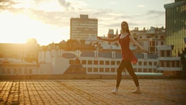 Mujer joven bailarina bailando en el techo - corre hacia arriba y saltar realizando una división - puesta de sol brillante — Vídeo de stock