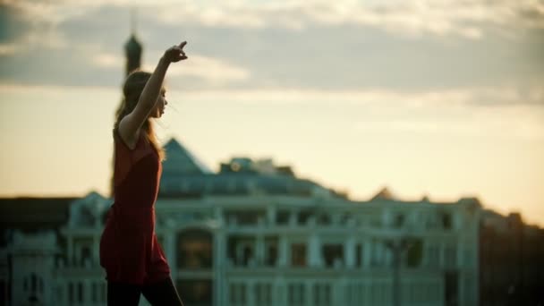 Mujer joven bailarina en vestido rojo bailando en el techo - corre hacia arriba y saltar realizando una división - puesta de sol brillante — Vídeos de Stock