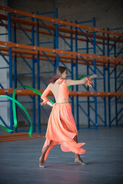 Joven mujer en forma bailando con cinta gimnástica en las manos en el almacén —  Fotos de Stock