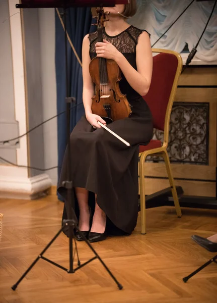 Una joven vestida de negro sentada en la silla sosteniendo violín —  Fotos de Stock